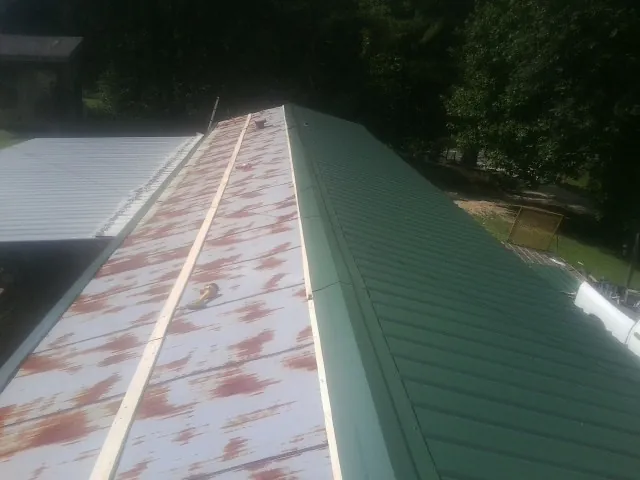 Old rusted panels beside newly installed green metal roofing — Wind Damage Roof Repair by Roofing Brothers in Matthews