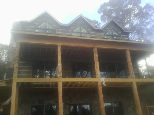 Dormers and porch framing on a large log home under construction — Roof Coating work by our crew in Matthews